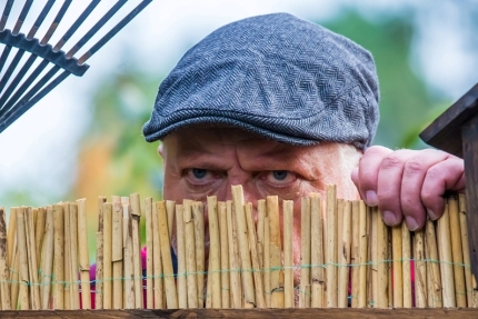 Nachbar schaut über Gartenzaun
